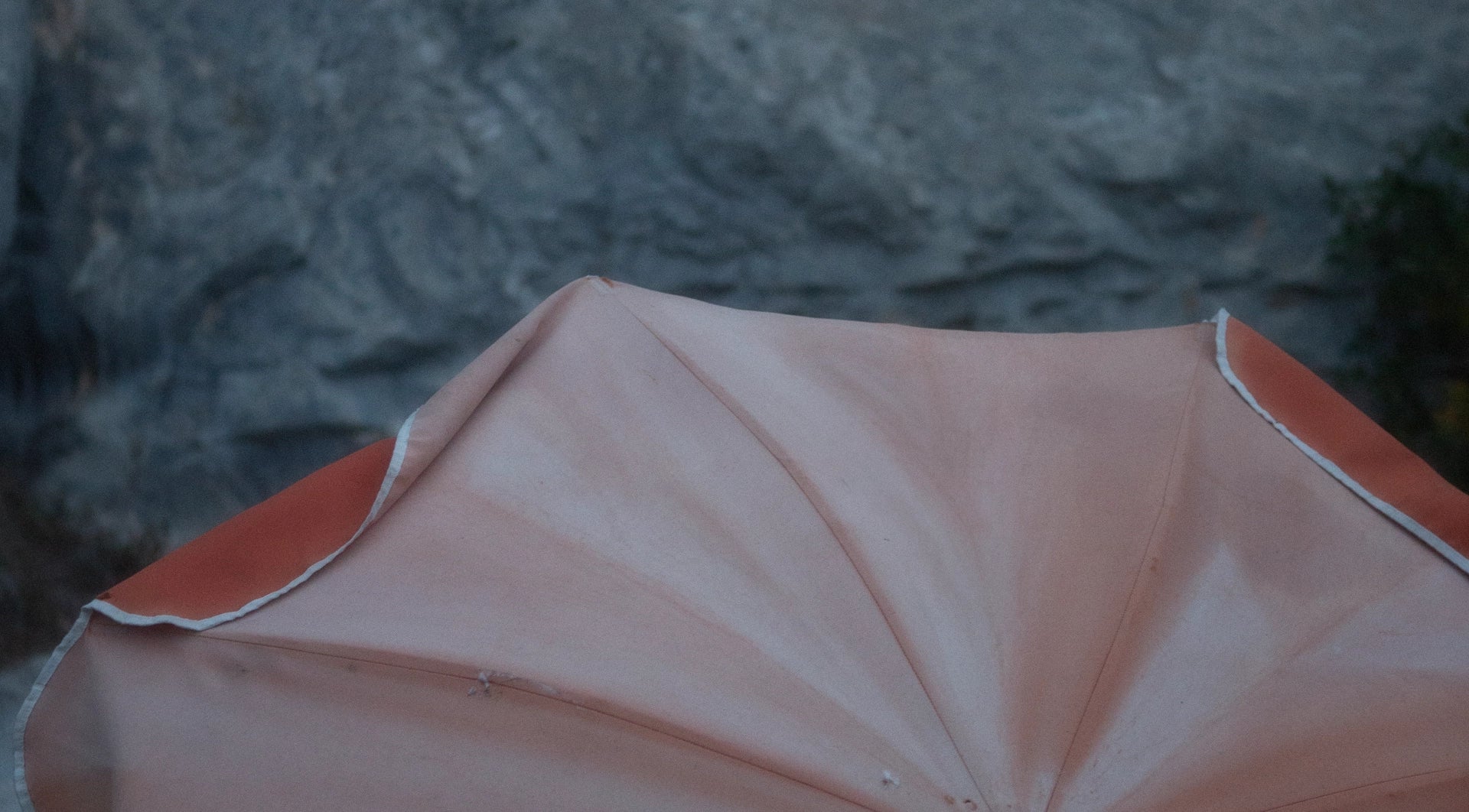 Old sun umbrella in front of rock face.