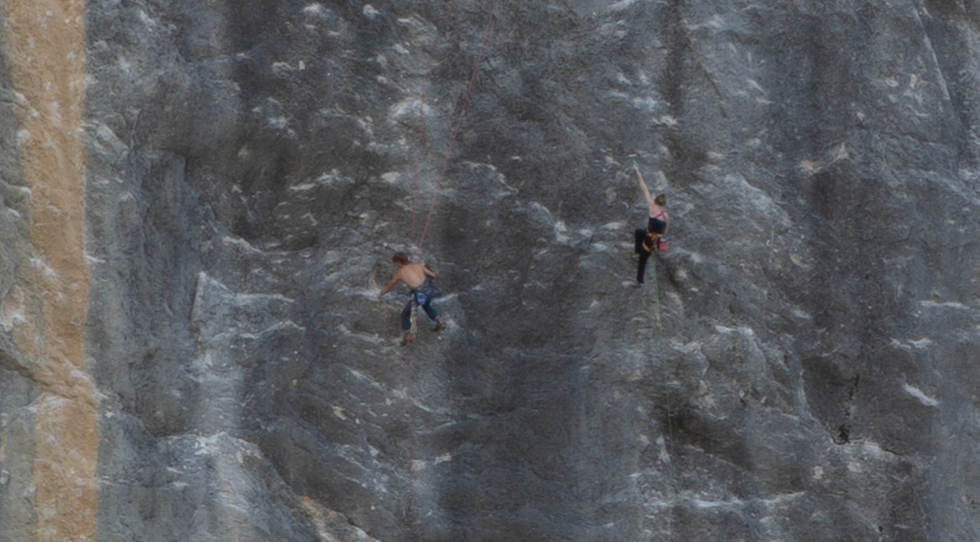 Rock climbes scaling on limestone in Ailefroide France.