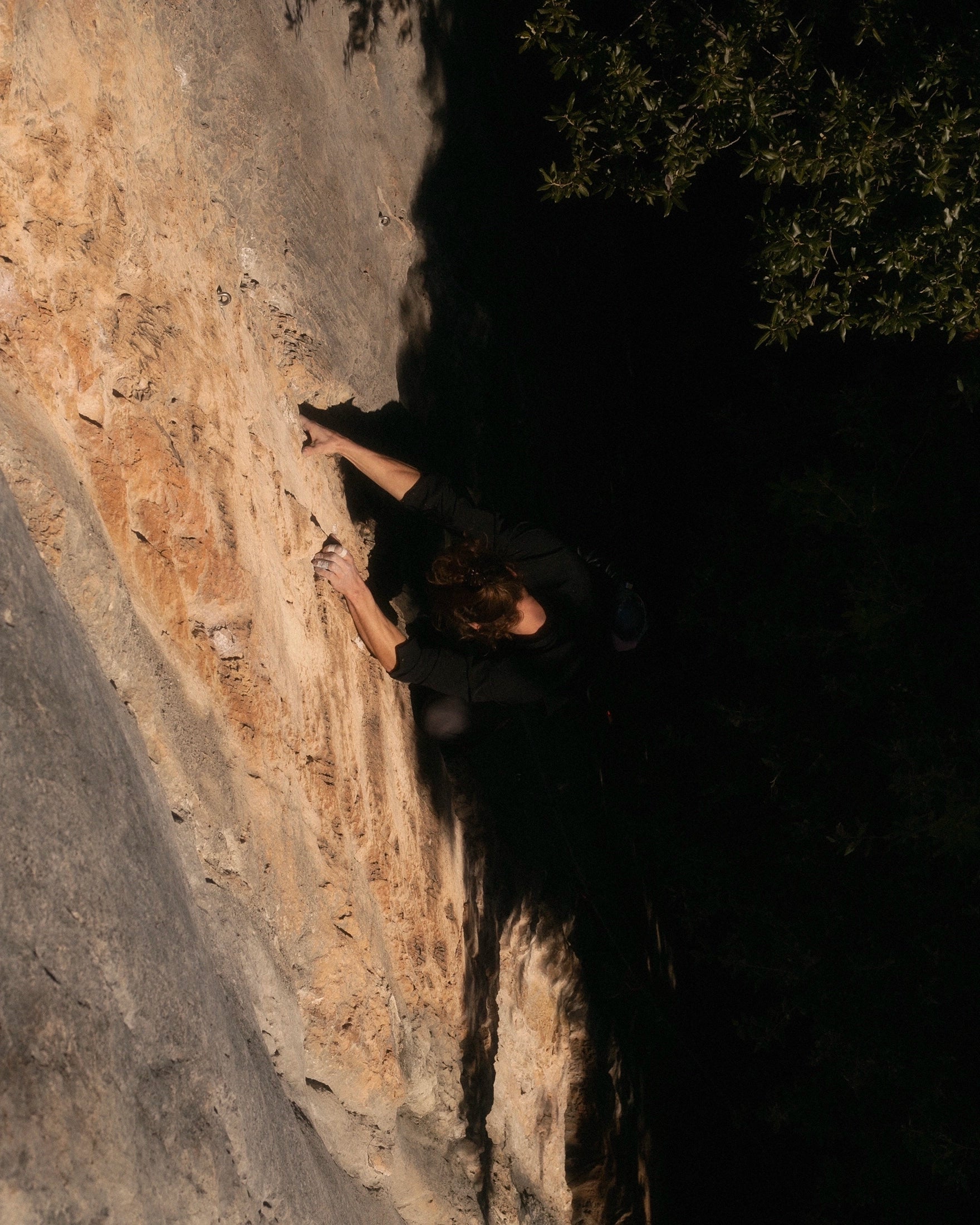 Climber ascending limestone wall in technical climbing apparel.